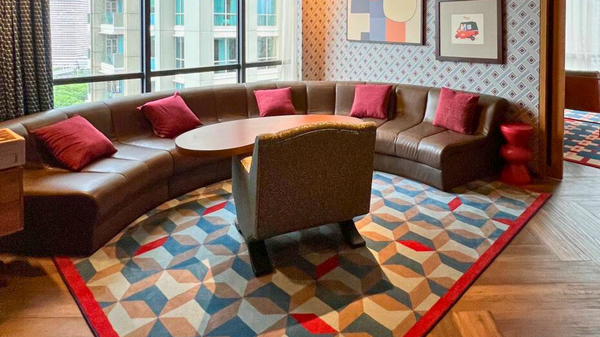 Stylish living room at 25hours Hotel Jakarta, equipped with a leather couch, coffee table, and a large window for natural light.