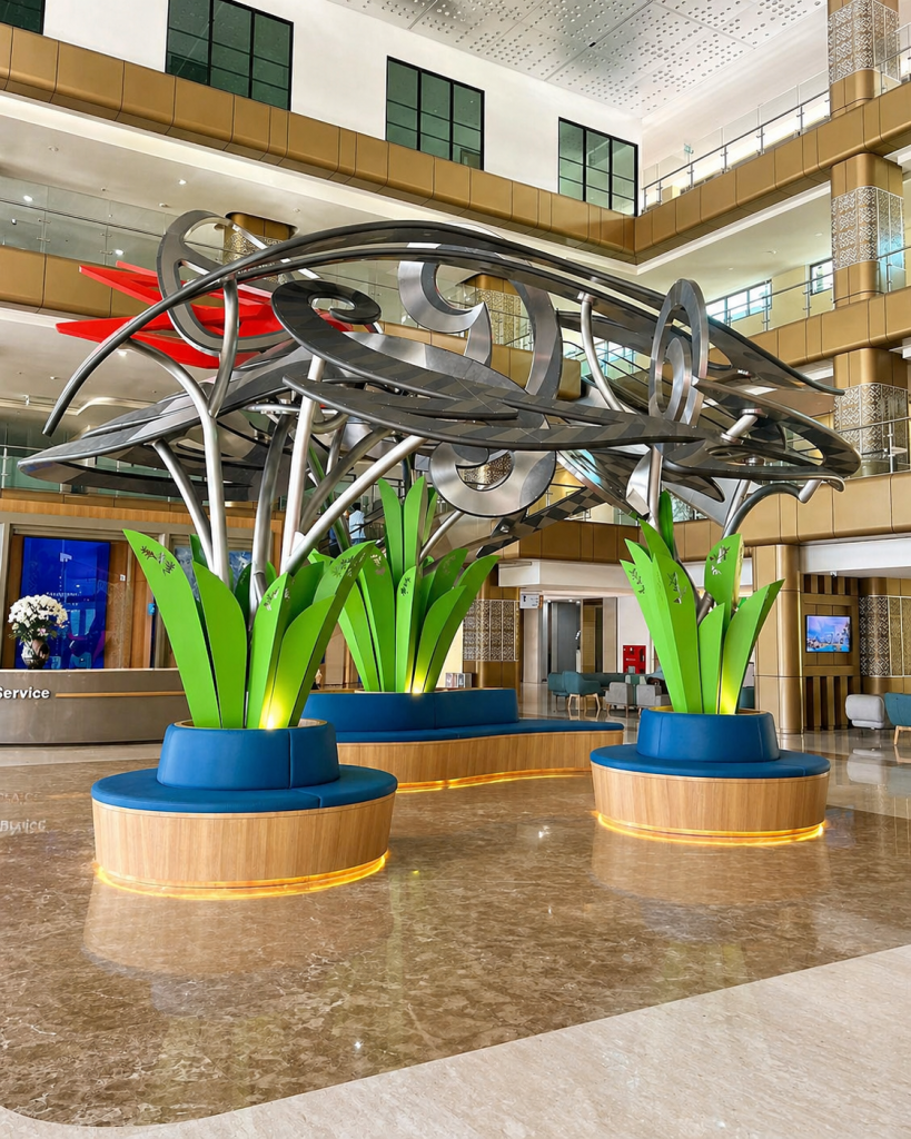 Spacious lobby at Bali International Hospital featuring a large modern sculpture, illuminated seating, and a bright multi-story atrium.